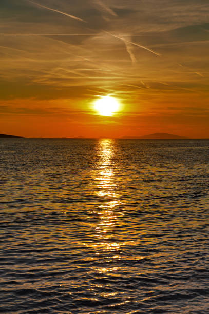Sea horizon between dramatic sky with clouds and chem trails above shiny and wavy sea surface