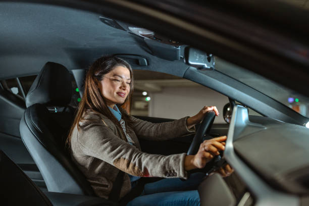 istock Professional woman driving a car while engaging with in-car technology 2196639211