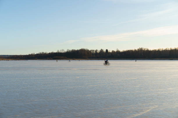 Örebro, Örebro Län, Sweden - 01.04.2025: People ice skating and playing on a frozen ice lake on a cold sunny beautiful winter day in Sweden.