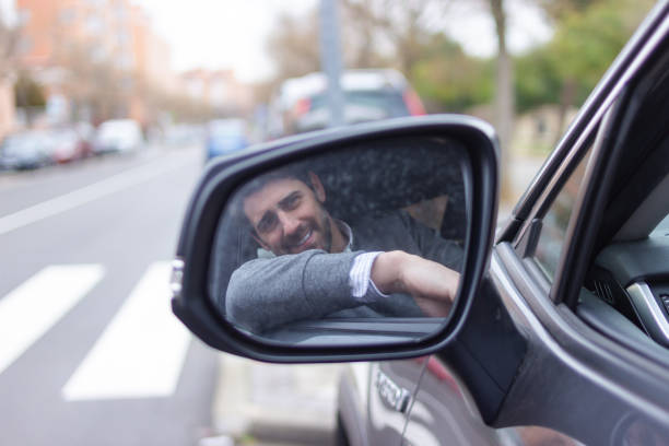 istock Businessman smiling at rearview mirror while driving car 2196643995