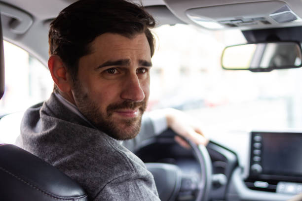 istock Businessman driving car and looking back over shoulder 2196644014