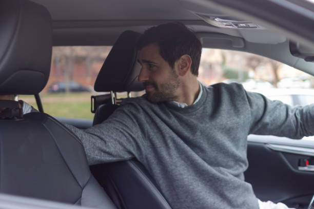 istock Young businessman turning back while driving a car 2196644567