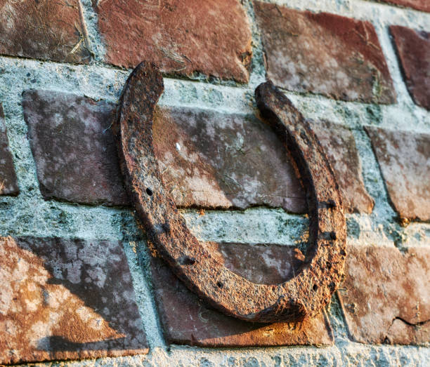 Close-up of a rusted horseshoe secured to an old brick wall, symbolizing tradition and good fortune, with warm sunlight creating a rustic and textured outdoor atmosphere, ideal for copy space.