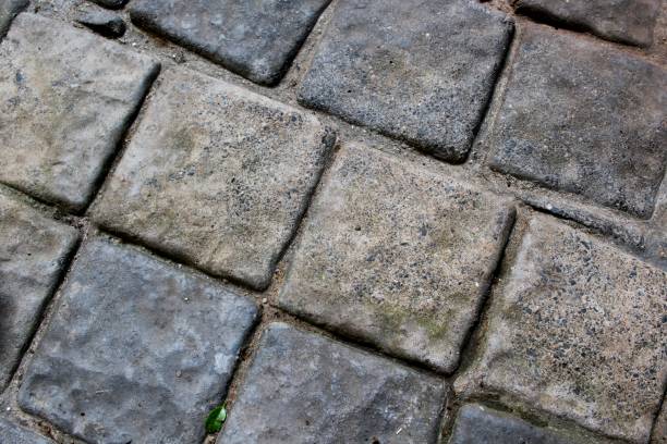 Detailed view of weathered stone tiles, highlighting their textured surface with natural wear. Ideal for use as a background with negative space for text or as architectural and construction design inspiration.