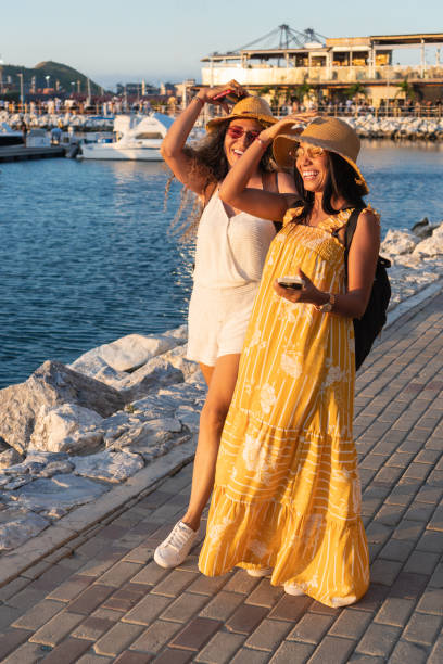 istock Two smiling women walking on a dock at sunset 2196656237