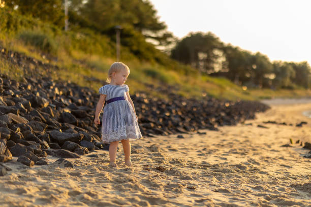 A girl in a black swimsuit is playing on the seashore.