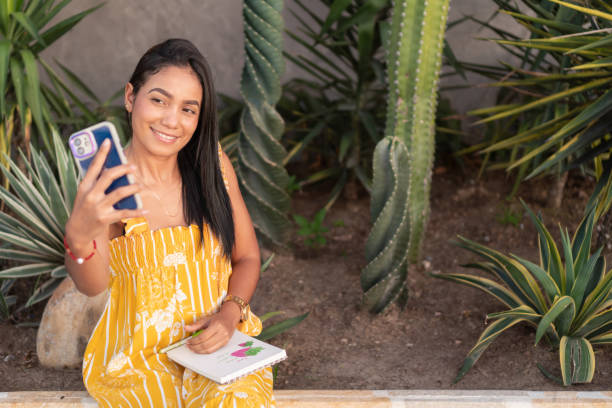istock Young latin woman taking a selfie while sitting in a botanical garden 2196660802
