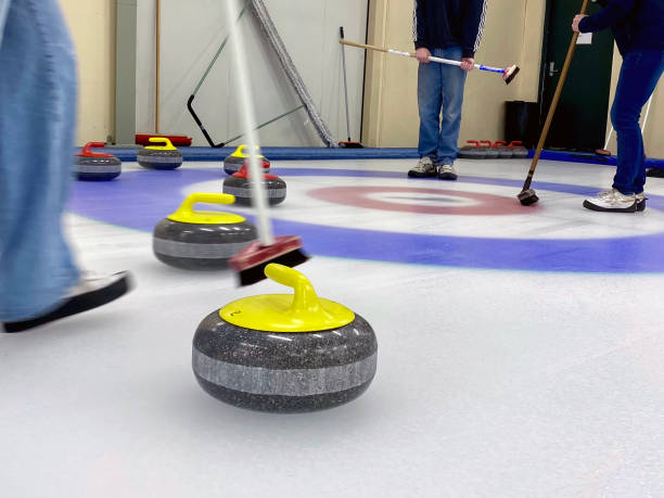 Curling games. The player is brushing the ice by directing the stone to the house