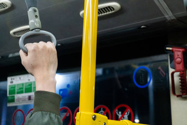 istock A hand grips a grey bus handle with a yellow pole in view, suggesting a commute or public transit ride. 2196671483