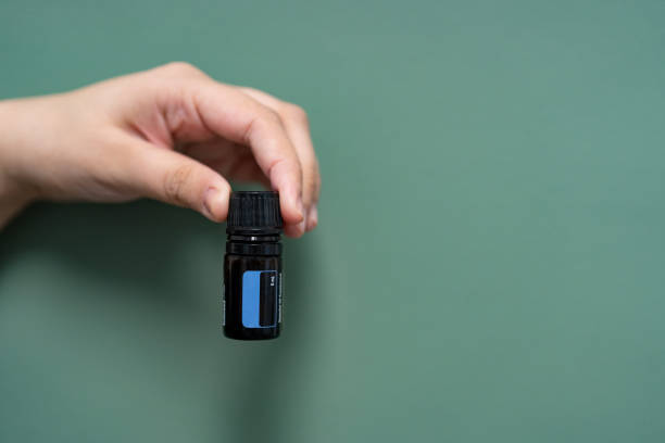 Person holding an essential oil bottle in front a green background