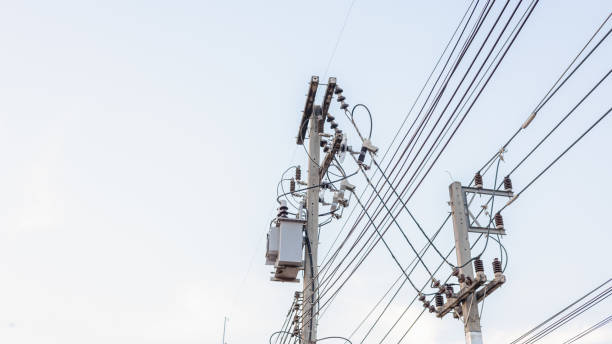 istock Electrical energy transfer distribution on concrete pole against white sky background, AC high-voltage power transformer, A low angle shot of a power transformer and electrical wires on a metal pole 2196678525