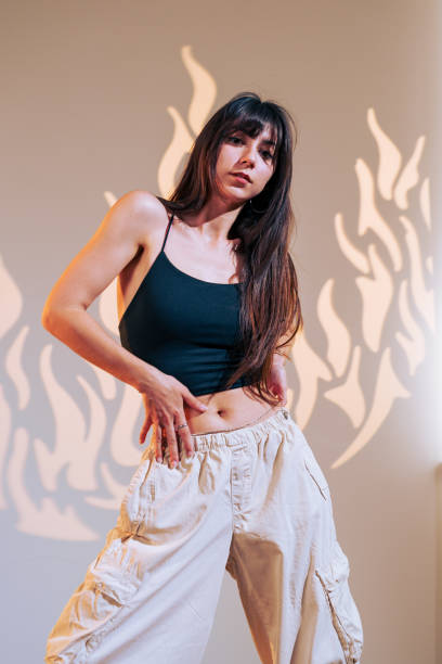 istock Dynamic dance session featuring a woman in a stylish outfit with artistic flame shadows on the wall 2196689235