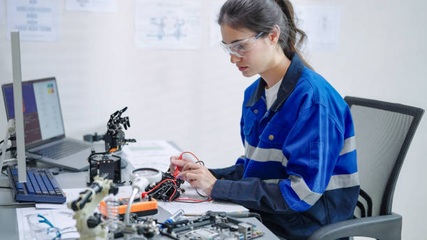 istock White woman engineer developer wearing safety protective goggles with blue work jacket is soldering intricate robotic components on a circuit board or an electronic device workshop in a laboratory room 2196689616