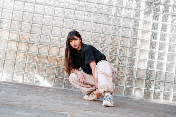 istock Young dancer poses in urban setting with glass brick wall during daylight hours 2196690038