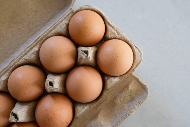 istock Organic brown eggs in a cardboard box on kitchen counter top view 2196691372