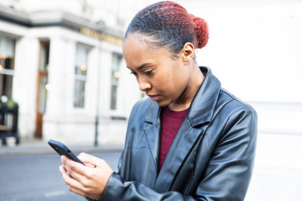 istock Young woman using a smartphone on a city street 2196691531