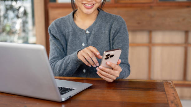 istock A satisfied Asian woman responds to messages on her phone while working remotely from a coffee shop. 2196691845