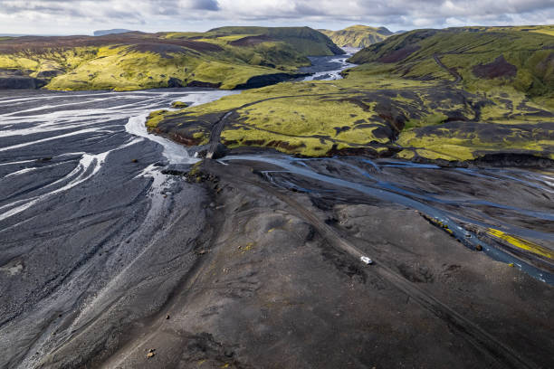 istock Aerial drone view exploring a river valley landscape with a lone white car 4x4 on a dirt road to Thakgil (Pakgil) campsite near Vik in Iceland 2196692111