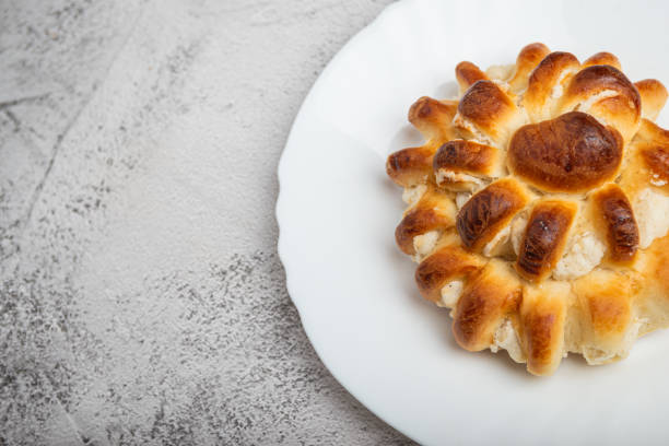 Close-up of a freshly baked stuffed bun on a white plate.