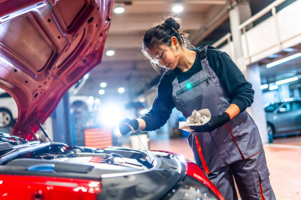 istock Female mechanic checking oil level in car engine at garage 2196694946