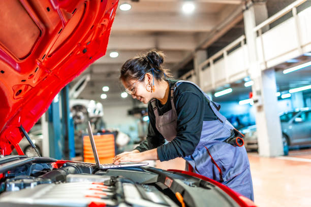 istock Female mechanic using laptop while repairing car engine in workshop 2196694960