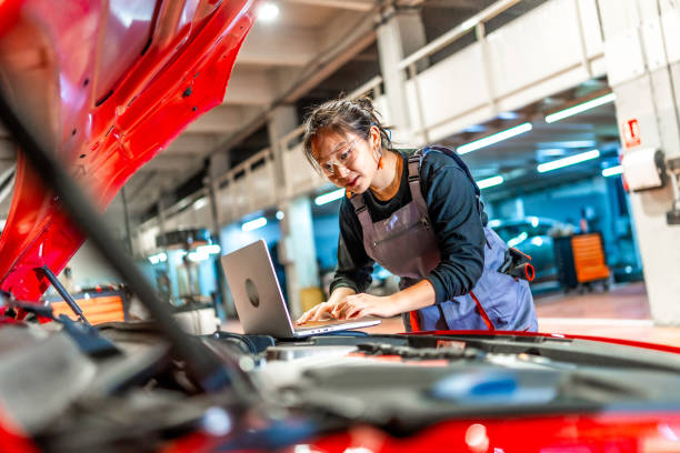istock Female mechanic using laptop while repairing car engine in workshop 2196694968