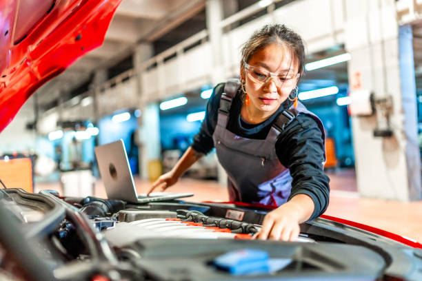 istock Female mechanic inspecting car engine with laptop in workshop 2196694971