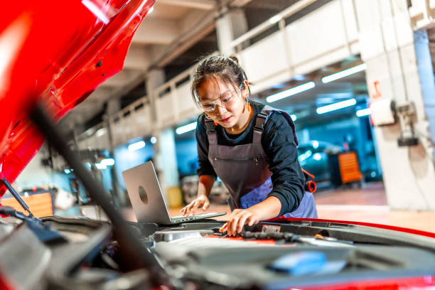 istock Female mechanic using laptop while repairing car engine in workshop 2196694974