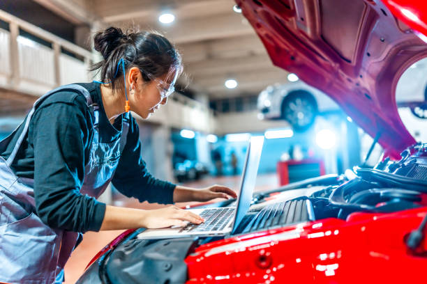 istock Female mechanic using laptop while inspecting car engine in auto repair shop 2196694981