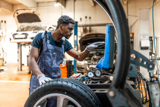 istock Mechanic changing car tire and using computer in auto repair shop 2196695224