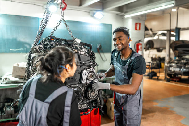 istock Mechanics working on suspended car engine in garage 2196695254
