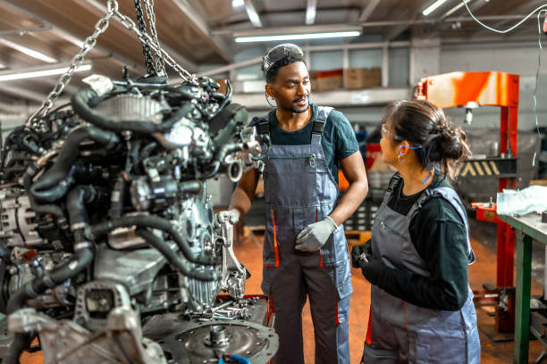 istock Mechanics working on suspended engine in car repair shop 2196695351