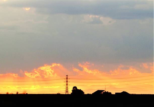 Sunset paints orange sky with silhouettes of grass and power lines viewed through camera viewfinder