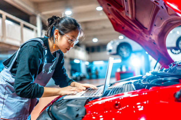 istock Female mechanic using laptop while inspecting car engine in auto repair shop 2196695783