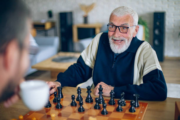 istock Senior man has a conversation with a volunteer while they play chess in the living room 2196696258