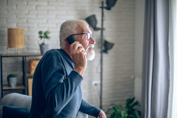 istock Senior man talking on the phone while he is home alone 2196696682