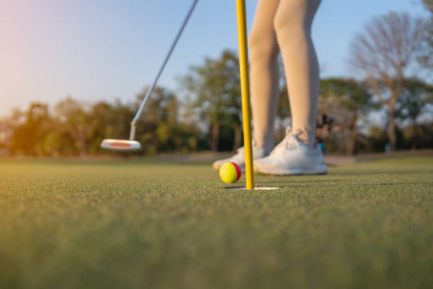 istock female golfer is putting the ball into the hole. 2196697897