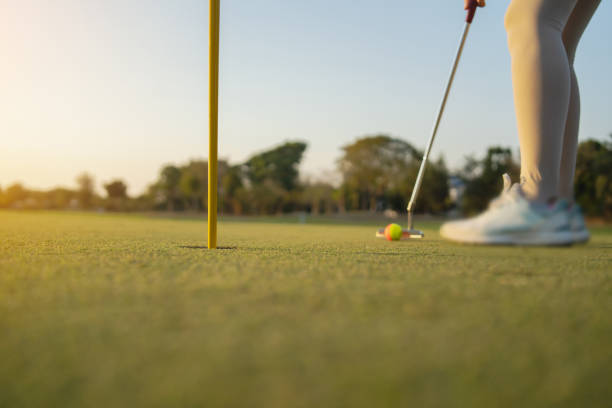 female golfer is putting the ball into the hole.