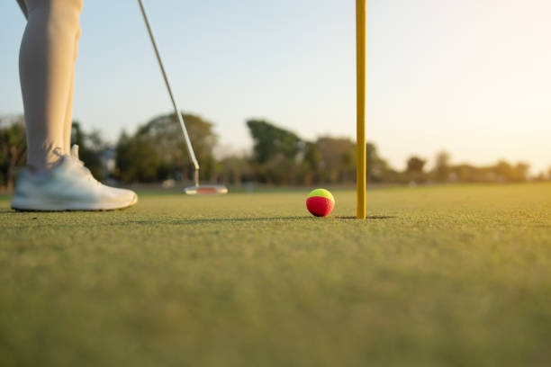 istock female golfer is putting the ball into the hole. 2196697909