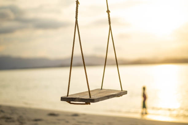 istock Wooden swing on beach at golden sunset. 2196698209