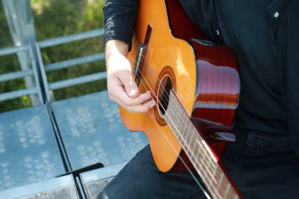 istock Man Tunes Guitar With Tuning Fork Outside 2196705777