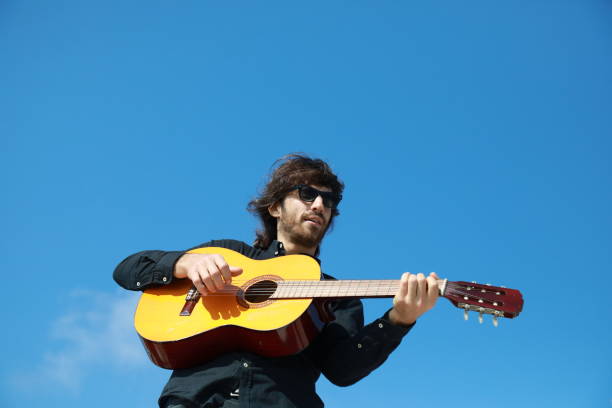 istock Young Long Hair Man Plays Classical Guitar Outside, Low Angle 2196706356