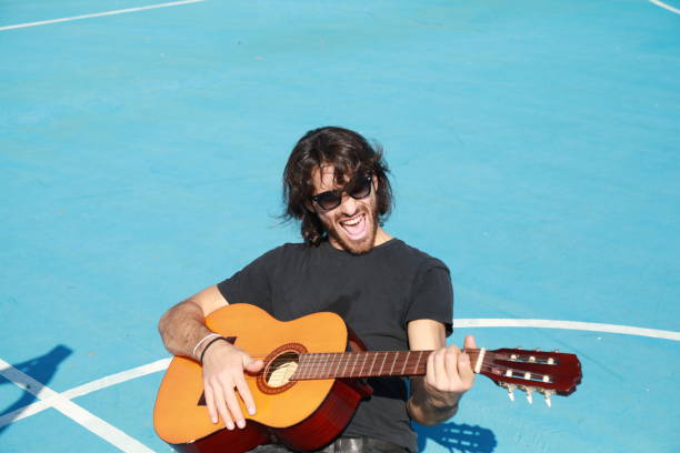 istock Long Hair Man Plays Classical Guitar Unleashed Outside In Blue Field 2196706490