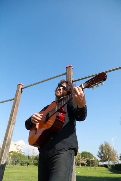 istock Young Man Classic Guitar Player Having Fun In The Park Outside 2196706587