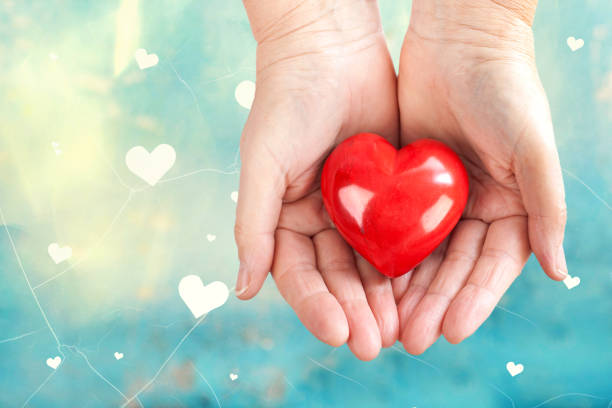 istock womans hands holding a glossy red heart, love concept 2196708383