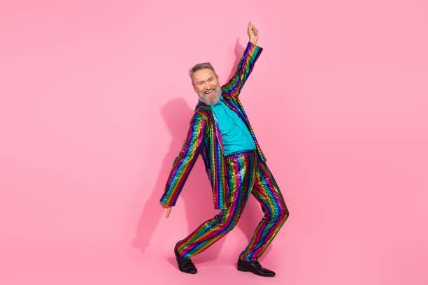 istock Handsome senior man in a colorful suit posing joyously against a bright pink background 2196712636
