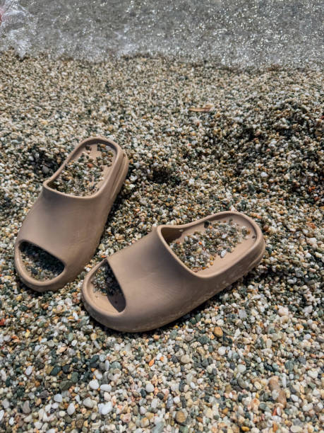 istock Pair of slippers on the pebble beach in summer 2196713143