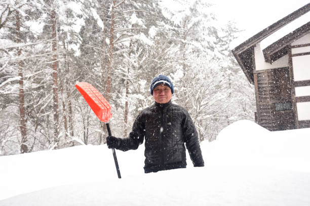 istock An old man clearing snow in a snowy area 2196714117