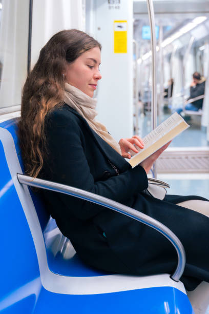 istock Side view Young Woman Reading a Book While Traveling on a Subway Train.,Vertical 2196714734