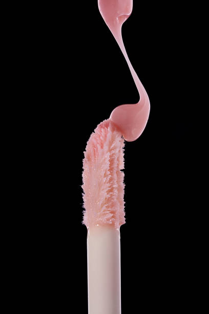 istock Drop of pink liquid lip gloss falls on applicator. Closeup shot on black background 2196716287